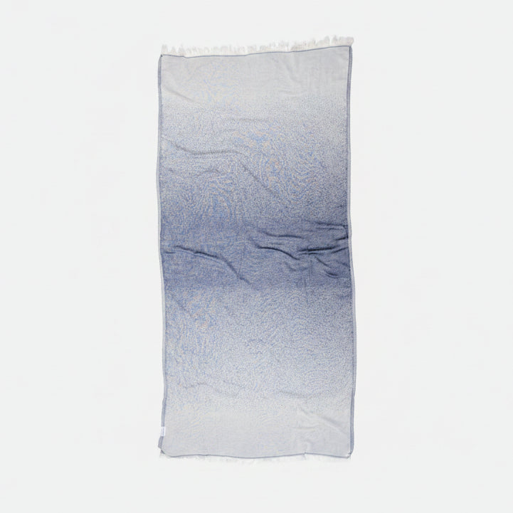 Ein elegant gefaltetes Ecobain Hamamtuch im Design Faded, Farbton Midnight Anchor. Der ausdrucksstarke Farbverlauf von tiefem Dunkelblau zu hellem Ecru entsteht durch eine aufwendige Jacquard-Webung. Gefertigt aus 100 Prozent langstapeliger, gekämmter Baumwolle, ist dieses ressourcenschonende und plastikfreie Tuch die smarte, platzsparende Alternative zu klassischem Frottee. Schnelltrocknend und besonders hautfreundlich – ein stilvolles Must-have für dein Badezimmer, Wellness oder entspannte Reisen.