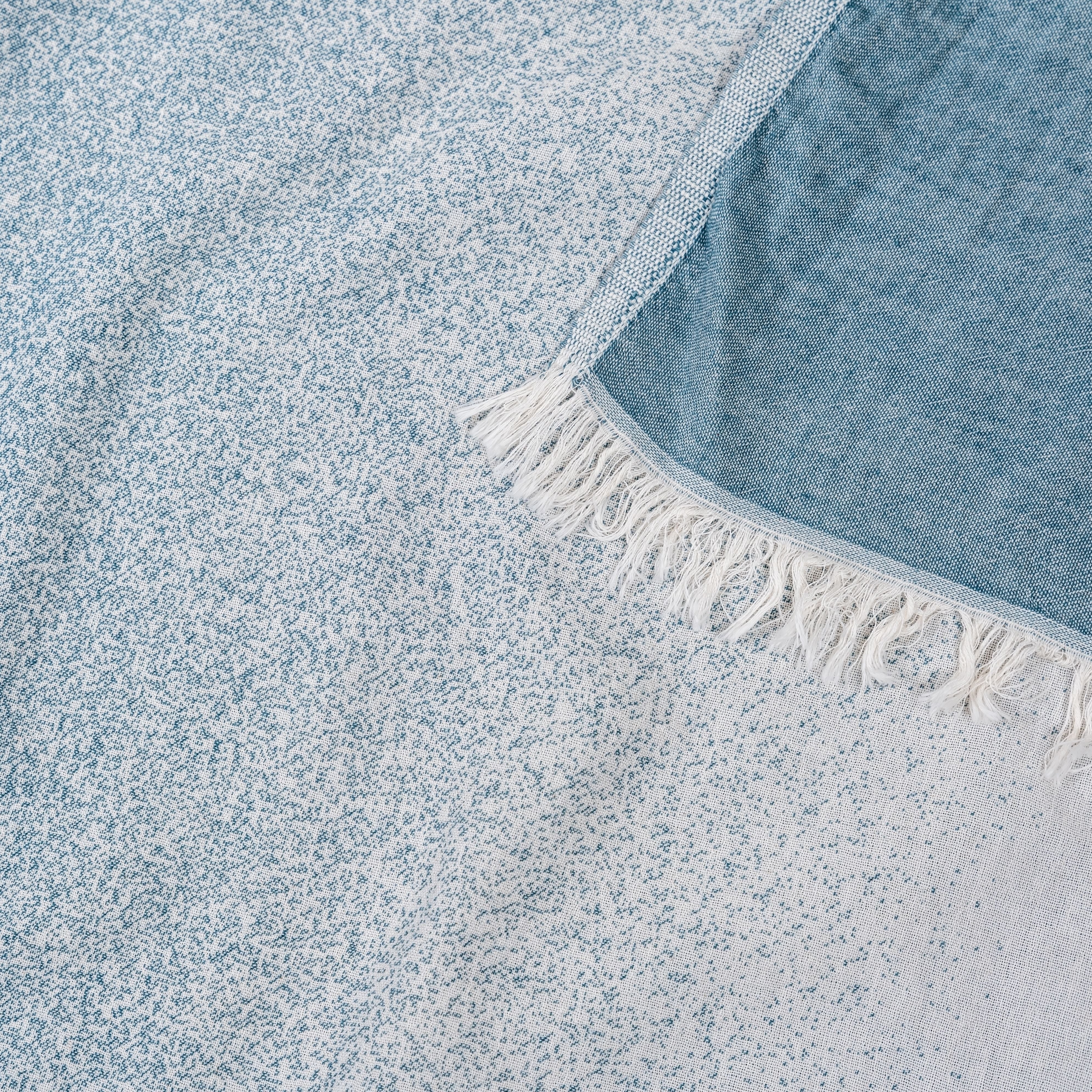 Detailaufnahme des Ecobain Hamamtuchs aus der Liberty Series im Design Faded, Farbton Sailors Dream. Das innovative Jacquard-Gewebe aus 100 Prozent langstapeliger, gekämmter Baumwolle erzeugt einen eleganten Farbfluss zwischen tiefem Petrol und hellem Ecru. Dieses ressourcenschonende, plastikfreie Tuch ist die smarte Alternative zu voluminösem Frottee. Extrem platzsparend, schnelltrocknend und besonders hautfreundlich. Ein ästhetisches Must-have für Wellness, Sauna und anspruchsvolles Interior Design.
