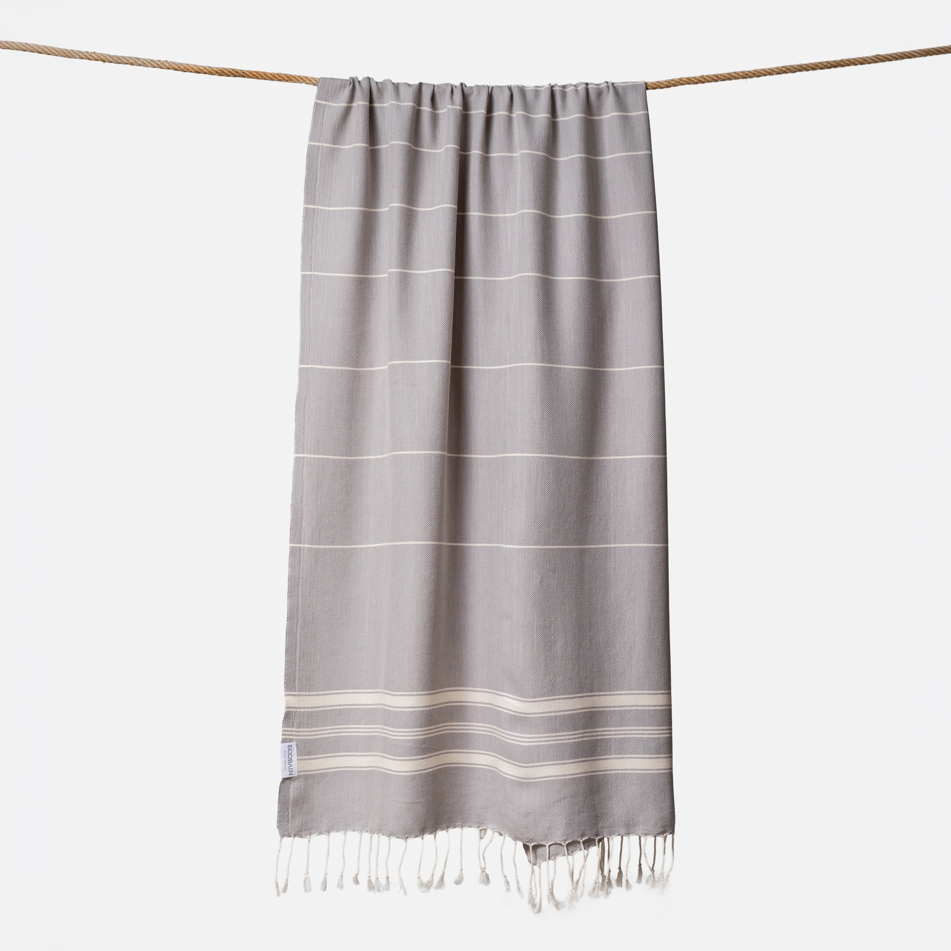 Extragroßes Ecobain Saunatuch der Liberty Series im edlen Silbergrau Moon Shadow. Das platzsparende Pestemal in 100x200 cm wird stilvoll gerollt mit originalem Hang Tag geliefert und ist die perfekte nachhaltige Geschenkidee für Wellness-Liebhaber. Ein schnelltrocknendes Hamamtuch aus pestizidfreiem Anbau, das in der Sauna oder im Home Spa schweres Frottee ersetzt und pure Leichtigkeit bietet.