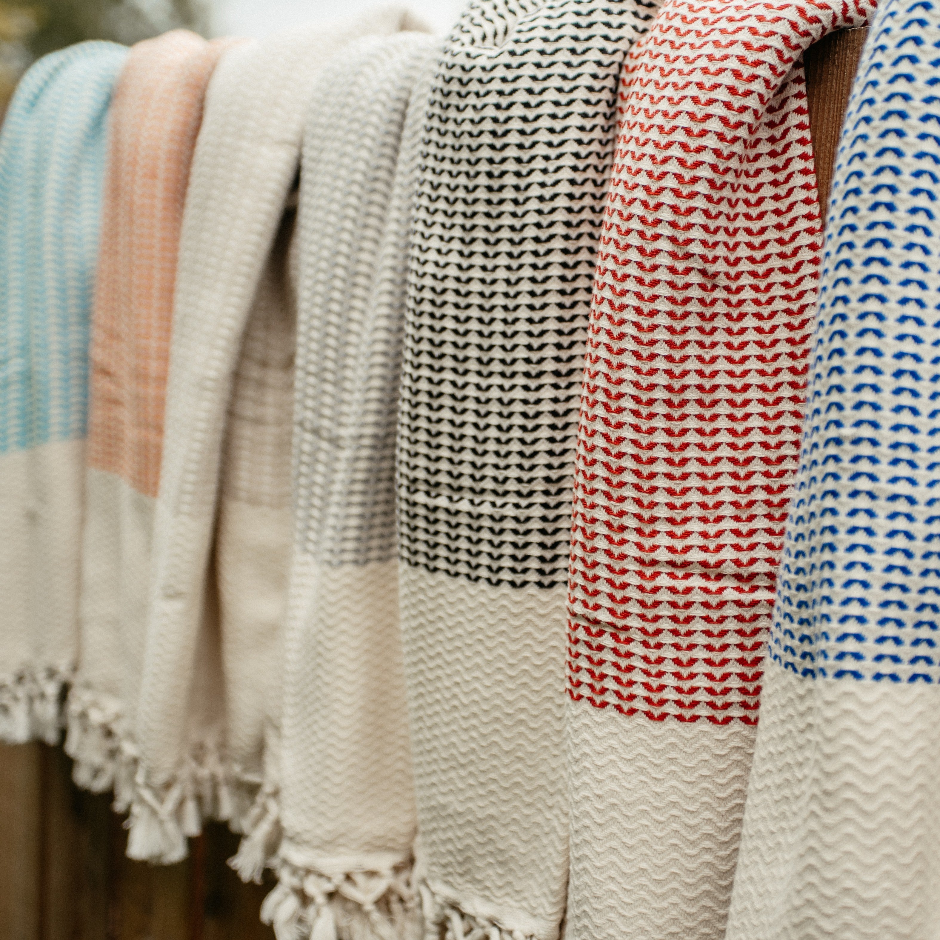 Ein türkisfarbenes Ecobain Gordion Towel, lässig über einen verwitterten Holzzaun im Freien gehängt.